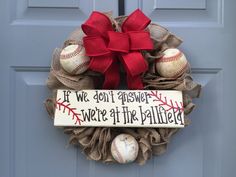 a wreath with baseballs and a bow hanging on the front door to say if we don't answer, we're at the ballfield