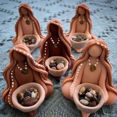 some little statues made out of clay with rocks in their bowls and pebbles in them