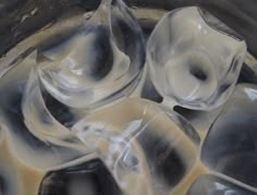 some ice cubes are sitting in a bowl with brown liquid on top and white stuff around them