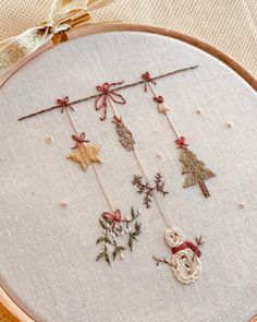 a close up of a embroidery on a hoop with some decorations hanging from the hoop