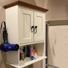 a white cabinet with hair dryer, blow dryer and other items on it