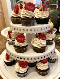 a three tiered cupcake display with coca - colas on it's sides