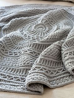 a knitted blanket laying on top of a bed