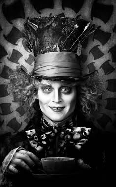 a woman dressed as mad hatter holding a coffee cup and looking at the camera