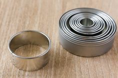 a metal ring sitting on top of a wooden table next to an empty tin can