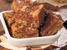 a white bowl filled with brownies on top of a wooden table