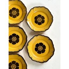 four yellow plates with black flowers on them