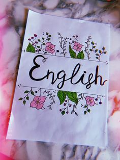 a piece of paper with the word english written on it next to some pink flowers