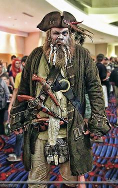 a man dressed up as captain jack sparrow in a convention hall with other people around him