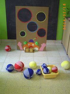 some balls are on the floor in front of a cardboard box