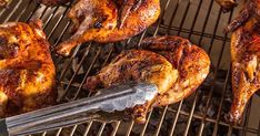 chicken wings being cooked on a grill with tongs