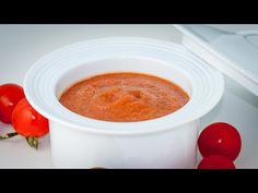 a white bowl filled with tomato soup next to tomatoes