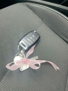 a car keychain with a pink ribbon tied around it's center console