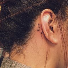 a woman's behind the ear has a small flower tattoo on her left side