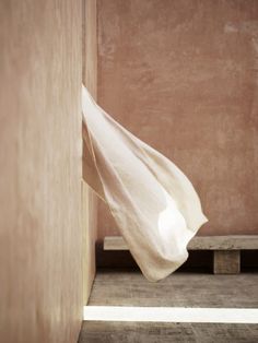 a white cloth hanging from the side of a wall next to a wooden bench in a room