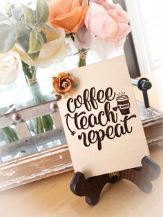 a sign that says coffee teach repeat on it next to flowers and a vase with roses