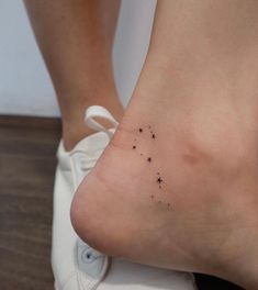 a small star tattoo on the foot of a woman's right leg, with stars all over it