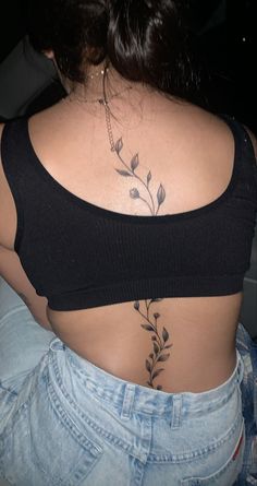 the back of a woman's stomach with flowers on her left side and leaves on her right side