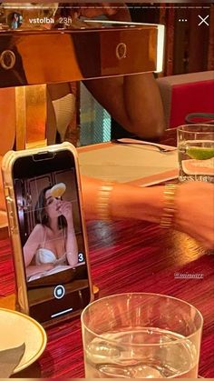 a cell phone sitting on top of a wooden table next to a glass filled with water