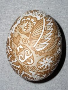 an egg with intricate designs on it sitting on a gray tablecloth covered flooring