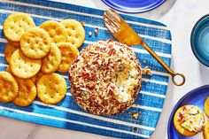 a blue plate topped with crackers next to a cheese ball and other food items