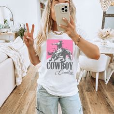 a woman taking a selfie in her living room wearing a cowboy t - shirt