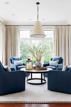 a living room filled with blue furniture and a round table in front of a window