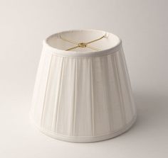 a white lamp shade with a gold cord