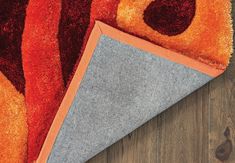 an orange and gray area rug on top of a wooden floor next to a piece of wood