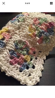 a crocheted dishcloth with multicolored flowers on it, sitting on top of a table