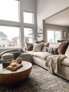 a living room filled with lots of furniture next to large windows on top of a carpeted floor