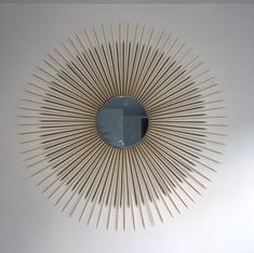 a sunburst shaped mirror hanging on the wall in a room with white walls