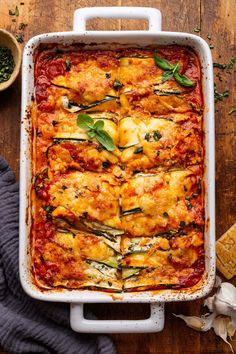 a casserole dish with zucchini and spinach in it on a wooden table