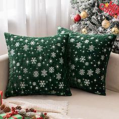 two green pillows sitting on top of a couch next to a christmas tree