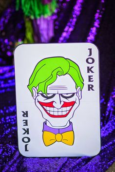 a joker playing card with purple sequins in the background