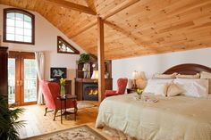 a bed sitting under a wooden ceiling next to a fire place in a living room