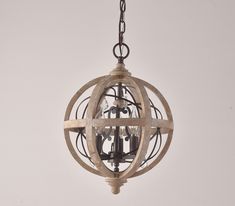 an old - fashioned wooden globe chandelier hanging from a chain on a white wall