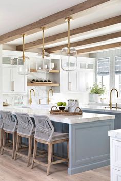 an instagramted photo of a kitchen with white cabinets and gray island in the center