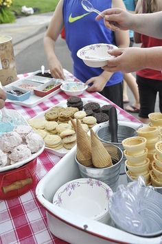 several people standing around a table with plates and desserts on it, including donuts