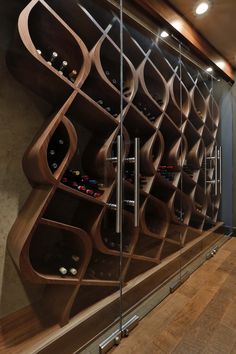 a wine rack in the corner of a room next to a glass wall with bottles on it