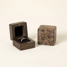 a wooden box with a ring in it sitting next to another box that has a wedding band inside