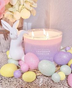 a candle sitting on top of a table next to some easter eggs and an bunny figurine