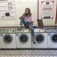 a woman sitting on top of a row of washing machines