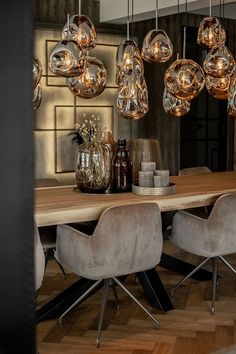 a dining room table with chairs and lights hanging from the ceiling