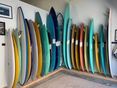 there are many surfboards lined up on the wall next to each other in this room