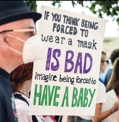 a man holding a sign that reads if you think being forced to wear a mask is bad imagine being forced to have a baby