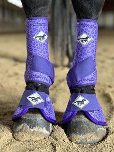 the legs and feet of a person wearing purple boots with leopard print on them, standing in sand