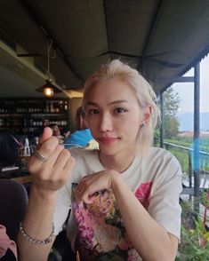 a woman sitting at a table with food in her hand and looking into the camera