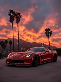 a red sports car is parked in front of some palm trees and the sun sets