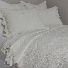 the bed is made with white linens and pillows